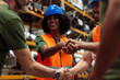 © bernardbodo - Happy workers shaking hands in warehouse, celebrating success
