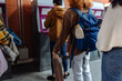 © bernardbodo - Students waiting in line at automated teller machine holding skateboard and backpack