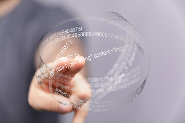 Hand points to a digital sphere filled with code.  Represents data, technology, or the internet.