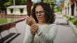 © Krakenimages.com - Woman with curly hair holding wrist in pain outdoors on a sunny street.