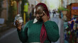 © Krakenimages.com - African american woman smiles while holding a jar containing a banknote in a bustling city street outdoors, suggesting financial planning and foresight.