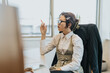 © qunica.com - A young professional woman wearing glasses, dressed in business attire, ponders during an office meeting. The scene captures concentration and business strategy in a modern workplace.