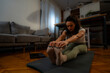 © DusanJelicic - A curly-haired woman embraces mindfulness, practicing yoga and meditation in the comfort of her living space.