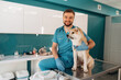 © standret - Looking at the camera. Male veterinarian is with Akita Inu dog in clinic