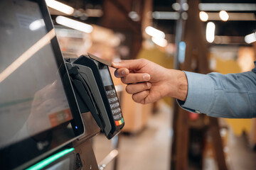 Wireless transfer. Close up view of man customer that is paying for products by credit card in grocery store