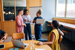 © (JLco) Julia Amaral - Group discussing ideas in office with laptops and presentation board