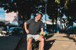 © Mdv Edwards - Southeast Asian man in his 50s sits on a park bench, wincing and holding his hip, possibly due to strain or joint pain after exercise.