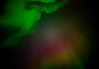 Wall Mural - colorful green, red and orange aurora northern lights in a stary night sky with a satellite trail