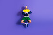 © deagreez - Young athletic man performing a jump in retro activewear against a bright purple background, expressing energy and vitality
