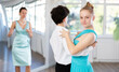 © JackF - Motivated adolescent ballroom dancers, girl and boy in performance outfit practicing elegant dance moves in pair in bright studio, with female coach supervising in background