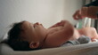 © Marco - Baby on changing table, mother’s hand holding diaper, child smiling softly, routine care, everyday moment, interaction with parent, comfort and care, intimate connection