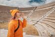 © EdNurg - Girl testing echo and acoustics at ancient amphitheater, concept of sound in historical architecture