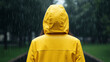 © Sana Sabina - Young person with yellow raincoat standing in the rain outdoors