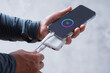 © vadish - Close-up of a man holding a power bank and charging a smartphone. Portable charger for phone and gadgets.