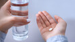 © Prostock-studio - Closeup view of young woman with glass of water taking antidepressants or sleeping pills. Unrecognizable millennial lady suffering from sleep deprivation or depression, overusing medical drugs