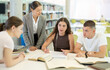 © JackF - Group of students talking, reading books and taking notes at table in library