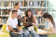 © JackF - Group of students reading and discussing books while sitting on chair in library