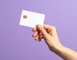 © SinemArt - Close up female hand holds levitating template mockup Bank credit card with online service isolated on purple background