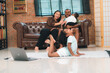 © chokniti - Heartwarming family moment as an African American father and daughter share playful time together on the couch, surrounded by love, laughter, and the warmth of home, while mom gently looks on with joy