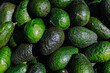 © Alejandro - Close-up of fresh green avocados piled in a woven basket at a local outdoor market. The natural lighting highlights their texture and ripeness, ideal for culinary, agricultural, or nutritional