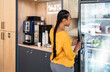 © VICTOR TORRES/Stocksy - Woman choosing beverage in modern office break area