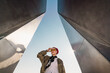 © Basil Pind/Stocksy - Person in red sailor-style hat standing between tall metal structures