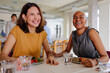 © BONNINSTUDIO/Stocksy - Businesswomen laughing together during lunch break at restaurant