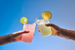 © Marc Tran/Stocksy - Two hands toasting with colorful, refreshing drinks under the sky
