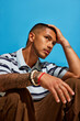 © Javier Díez/Stocksy - Man with tattoos ponders against a vibrant blue background