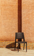 © VICTOR TORRES/Stocksy - Lone chair against textured orange wall in sunlight