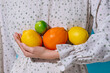 © Marc Tran/Stocksy - Fresh Citrus Fruits Held Against a Floral Patterned Dress