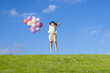© mei - A little girl is playing with a balloon on the grass under the blue sky and white clouds