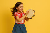Little girl smiling, playing a drum in a sunny park, surrounded by colorful flowers and trees.