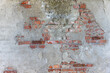 © Alexandra - Weathered concrete wall with peeling plaster revealing red brick underneath, featuring cracks, stains, and signs of urban decay.