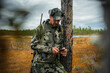 © Johnér - Male army officer wearing military uniform using smart phone while standing near tree