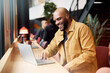 © Johnér - Happy bald male entrepreneur using laptop while sitting at table in office