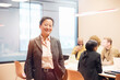 © Johnér - Portrait of smiling mature female business professional standing with hand in pocket at office