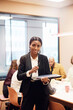 © Johnér - Portrait of smiling businesswoman standing with laptop in meeting room at office