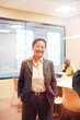 © Johnér - Portrait of smiling mature female entrepreneur standing with hands in pocket at office