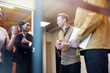 © Johnér - Low angle view of male entrepreneur holding mug talking with female coworker in office corridor