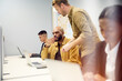 © Johnér - Male entrepreneur talking with coworker looking at laptop while sitting in office