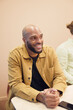 © Johnér - Smiling male business professional with hands clasped sitting in board room at office