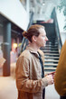 © Johnér - Male businessman with hair bun holding mug standing in office lobby