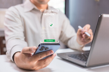 a person uses a smartphone to make a secure online payment with biometric authentication near a lapt