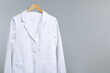 © New Africa - Doctor's coat on hanger against grey background. Space for text