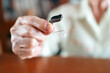 © artitwpd - Close-up of senior woman’s hand holding a hearing aid, illustrating elderly care, hearing support, and daily assistive technology use for aging populations in a clear and focused setting.