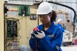 © amorn - Electrician woman, Electric system on circuit board, Ampere meter. Female electrician worker checking operation electric system on circuit board in factory. Electric engineer using ampere meter tool