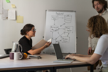 three software developers brainstorming in a modern office. team coding session with laptops showing