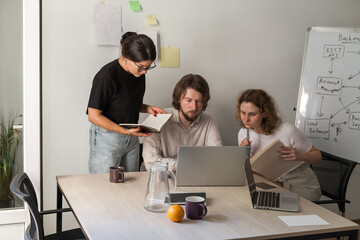three software developers brainstorming in a modern office. team coding session with laptops showing