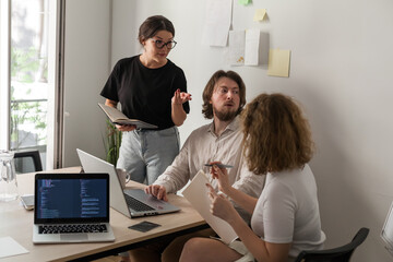 three software developers brainstorming in a modern office. team coding session with laptops showing